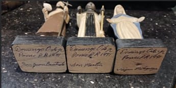 View of artist's signature on wooden plinth bases of saint figurines